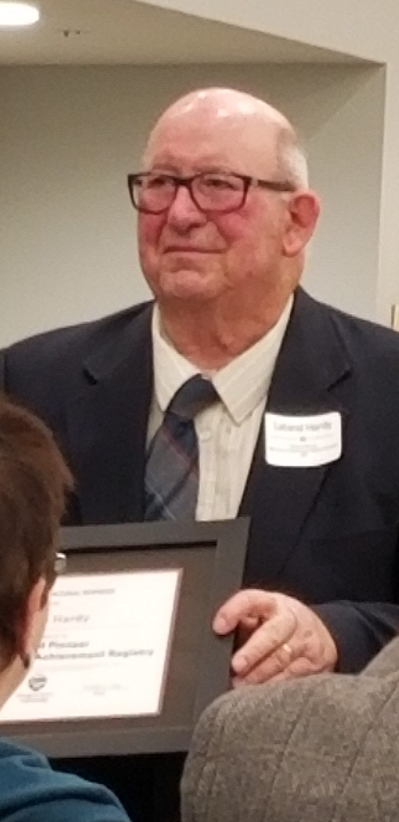 Lee at a meeting holding a certificate