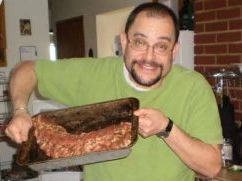 Tom grinning and holding a tray of ribs.