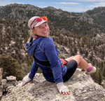 Chelsea sitting on a cliff overlooking a valley.