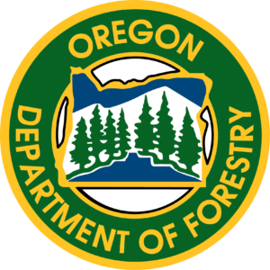 a yellow outlined green circle with the words Oregon Department of Forestry around the outside and inside is the state of oregon with blue top and bottom and white center with green conifers across