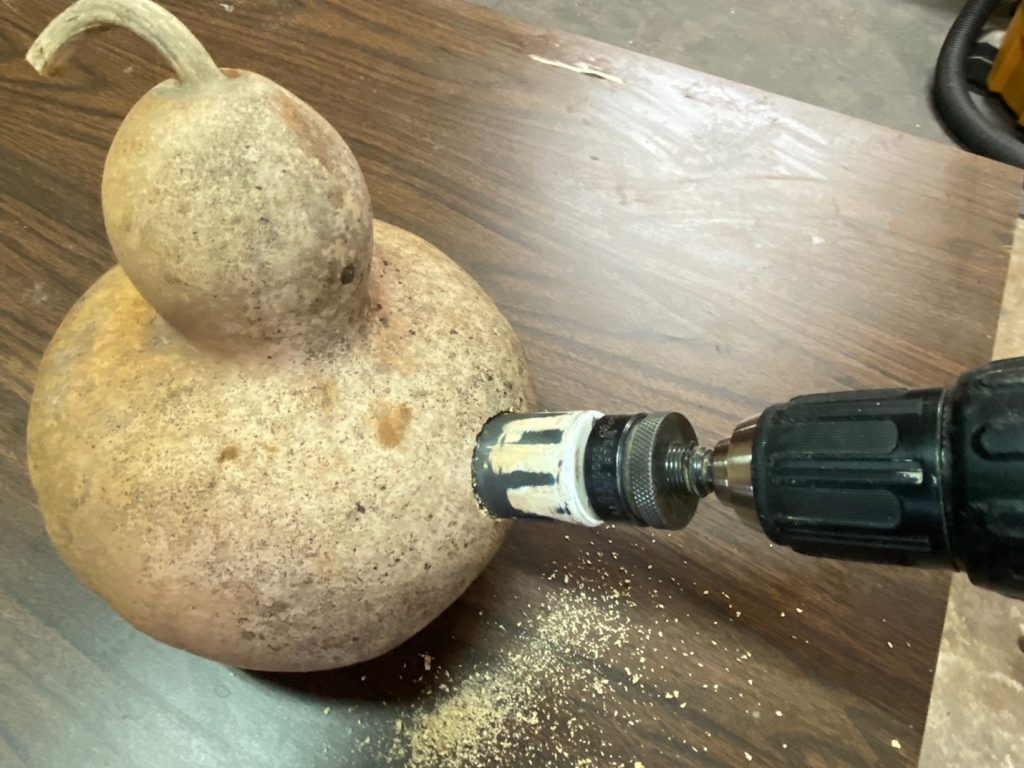 A drill is being used to create an opening in the gourd