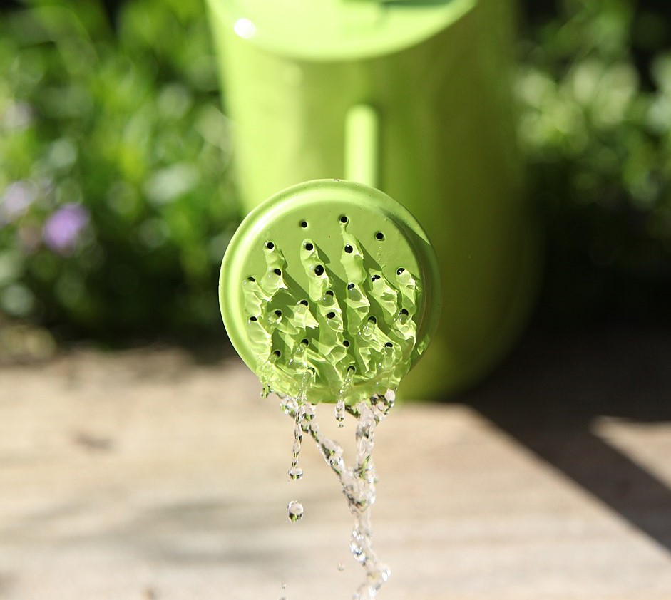 A green watering can pouring out water.