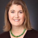 a head shot of Bonny with shoulder length light brown hair and a green bead necklace