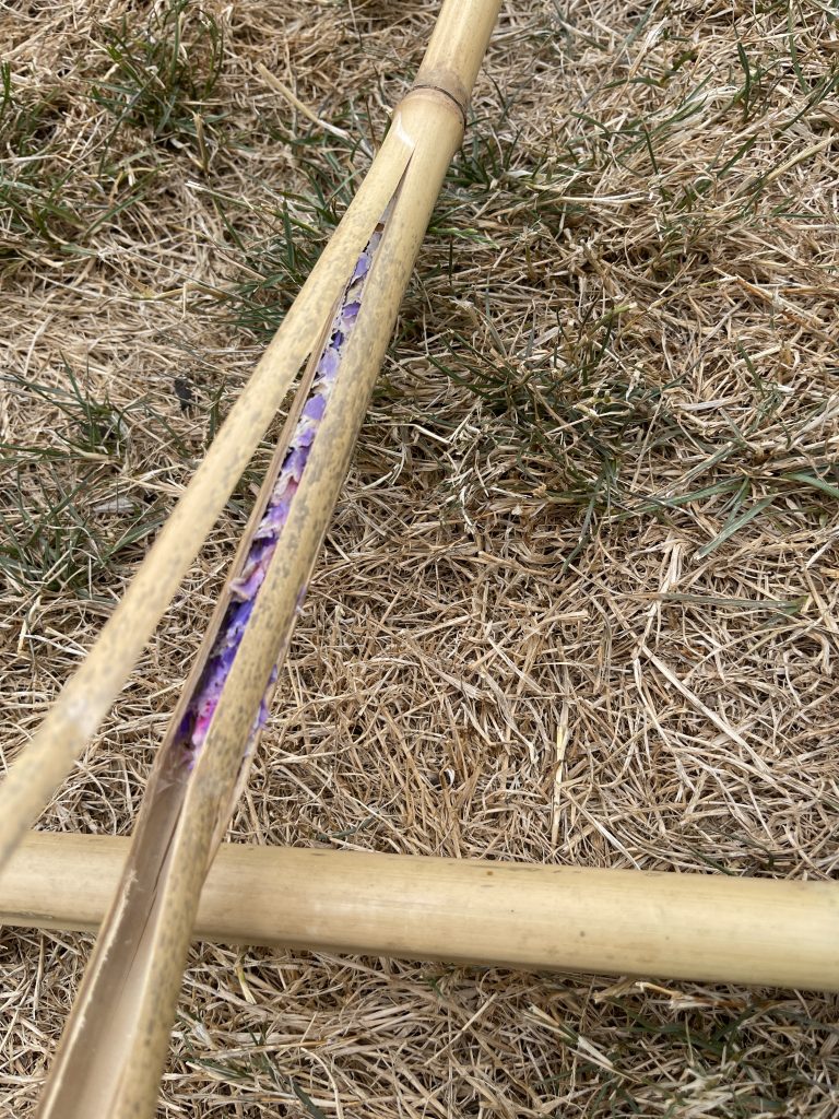 bamboo stick with a bee nest made from purple flowers