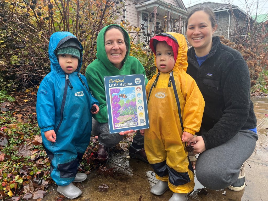 a family with two small kids holding a certification sign