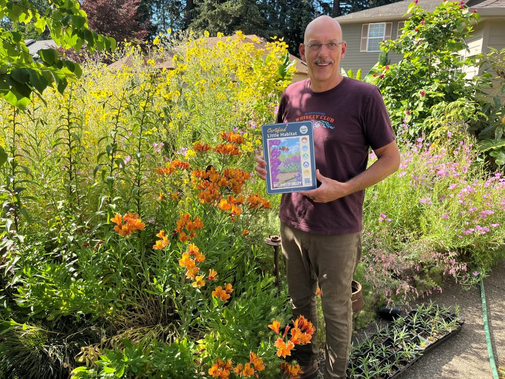 a man holding a sign in a flower garden