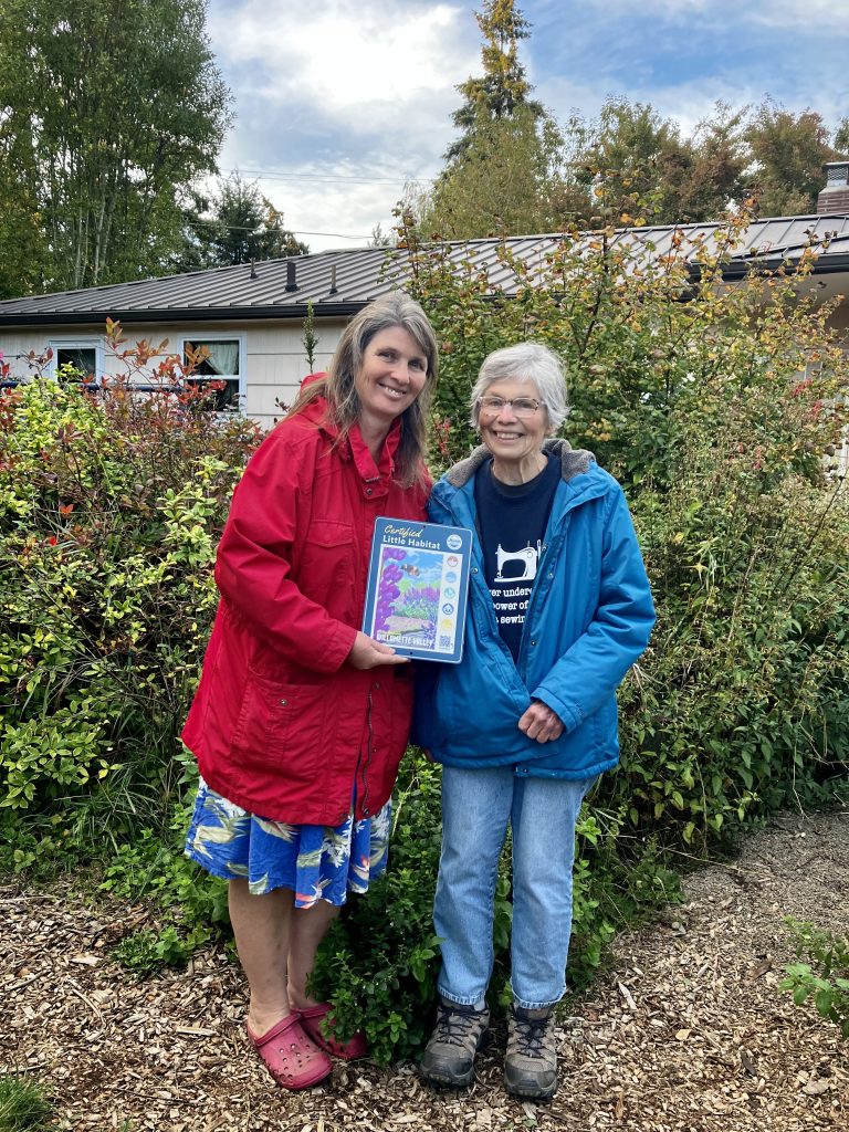 two women holding a certification sign