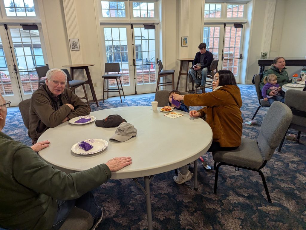 Three people around a table indoors, enjoying each other's company.